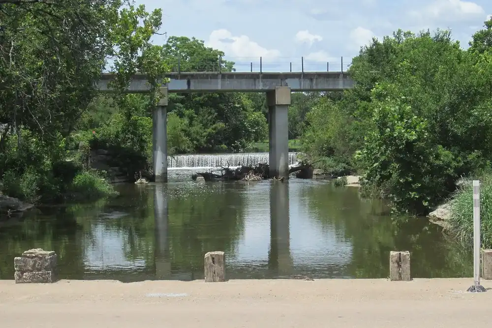 Creek with a low dam and a bridge behind it in Round Rock, Texas